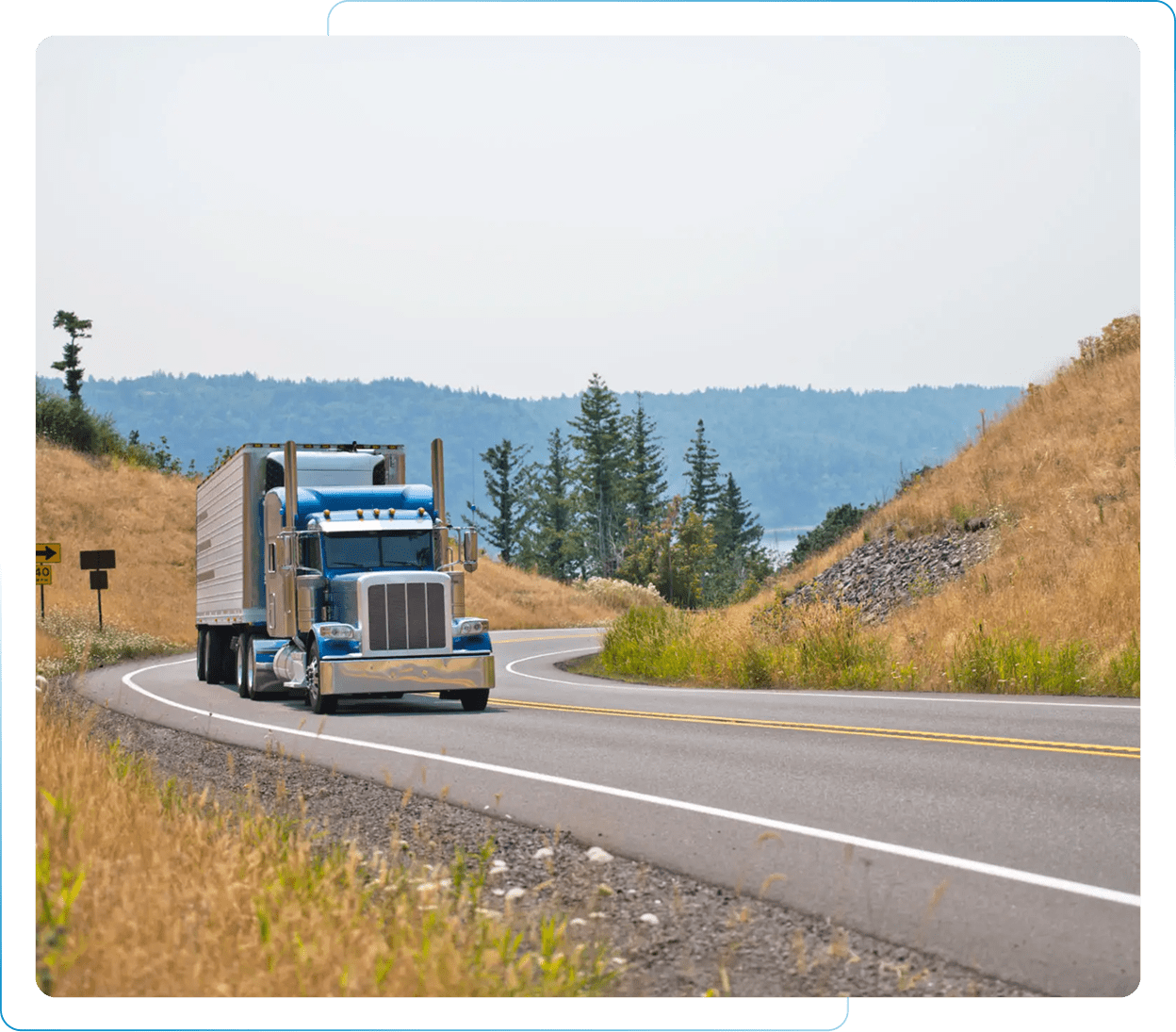 A large semi-truck driving on a highway through a mountainous area.