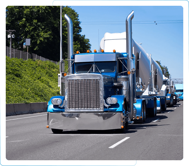 Blue semi-trucks driving on a highway in a convoy.